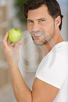 handsome man eating fresh healthy green apple