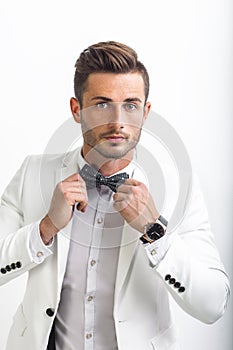 Handsome man in elegant suit adjusting his bow tie