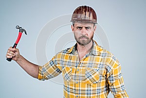 handsome man employee in construction safety helmet and checkered shirt on building site with hammer, tool shop
