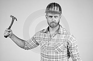 handsome man employee in construction safety helmet and checkered shirt on building site with hammer, tool shop