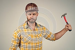 handsome man employee in construction safety helmet and checkered shirt on building site with hammer, tool shop