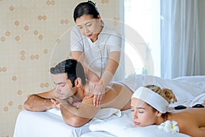 Handsome man enjoy with Thai masseuse massage to him and he lie on bed with his girlfriend in spa room with day light