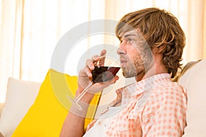 Handsome man enjoying a glass of wine on the couch