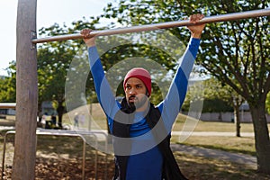 Handsome man exercises outdoors at an urban outdoor gym. Exercising after work for good mental health, physical health