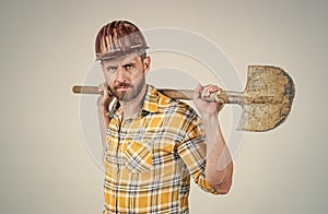 handsome man expert in construction safety helmet and checkered shirt on building site with shovel, occupation