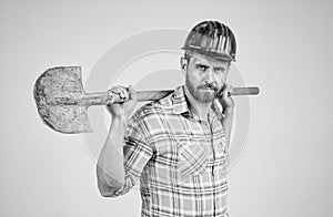 handsome man expert in construction safety helmet and checkered shirt on building site with shovel, occupation