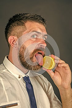 Handsome man face. Man with long beard lick lemon.