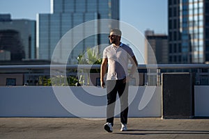Handsome man in fashinable outfit walking on city street. Successful male model in big city living the urban lifestyle
