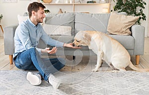 Handsome man feeding his dog in the living room