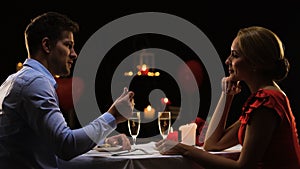 Handsome man feeding pretty lady, couple having romantic dinner at restaurant