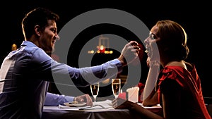 Handsome man feeding pretty lady, couple having romantic dinner at restaurant