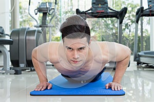 Handsome man fitness exercising by doing push ups as part of bodybuilding training in the fitness center