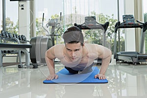 Handsome man fitness exercising by doing push ups as part of bodybuilding training in the fitness center