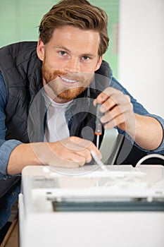 handsome man fixing photocopier during maintenance