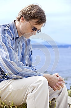 Handsome man in forties praying by side of lake