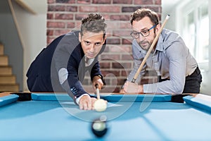 Handsome man friends playing snooker pool table game