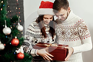 Handsome man giving christmas present to his beautiful woman in