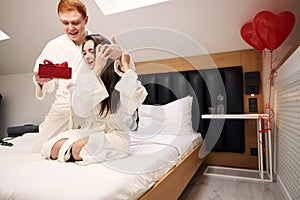 Handsome man giving present to his girlfriend in hotel room