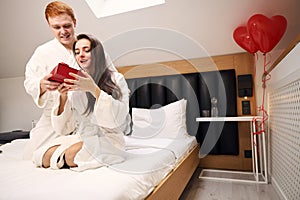 Handsome man giving present to his girlfriend in hotel room