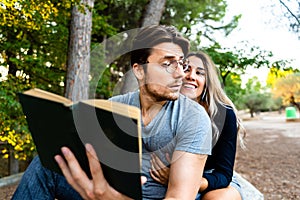 Handsome man with glasses seduces young woman reading him a book