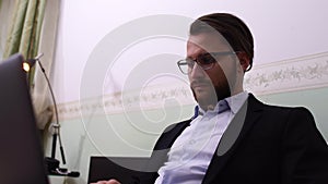 Handsome man with glasses works at laptop at home