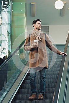 Handsome man going down on escalator and