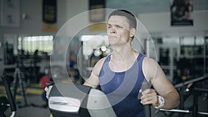 Handsome man at the gym exercising on the strainer machine. Left 3/4 face portrait