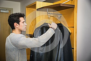 Handsome Man Hanging his Coats Inside his Wardrobe