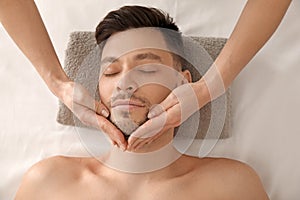 Handsome man having facial massage in spa salon