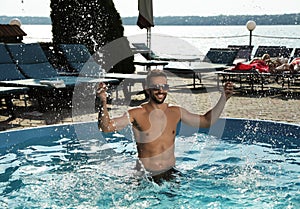 Handsome man having fun in outdoor swimming pool on day