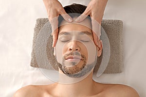 Handsome man having head massage in spa salon