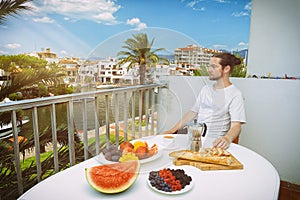 Handsome man having healthy breakfast on hotel terrace