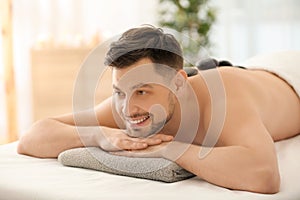 Handsome man having stone massage in spa salon