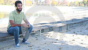 Handsome man with headphones listening to music on smartphone at park