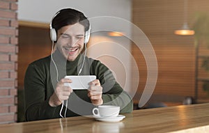 Handsome man in headphones listening to music, using smartphone