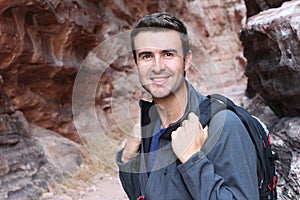 Handsome man hiking in rocky canyon, backpacker walking in the nature