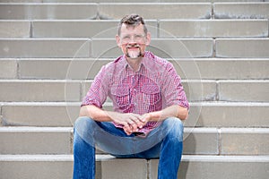 Handsome man in his 50s sitting on steps and smiling