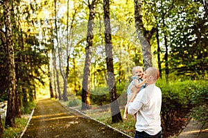 Handsome man hold in arms beautiful baby girl at the park, young father kissing little daughter, hugging, cute toddler