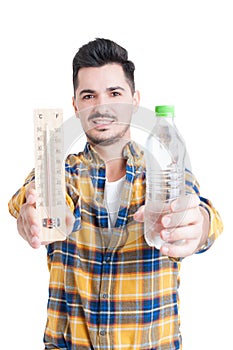 Handsome man holding a bottle of water and a thermometer