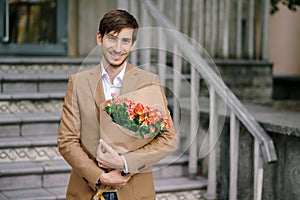 Handsome man holding bouquet of roses smiles showing teeth