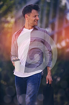Handsome man holding disposable cup and bag