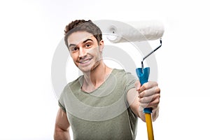 Handsome man holding paint roller and looking at camera isolated on white