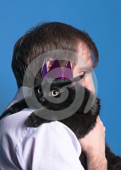 handsome man holding on sholder black cat in pink shiny crown photo