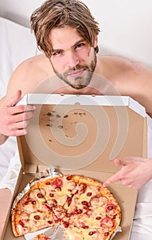 Handsome man holds a piece of pizza in his hands and is about to eat it. Cropped image of shirtless man with pizza