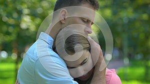 Handsome man hugging his beloved girlfriend, calming and comforting, close-up
