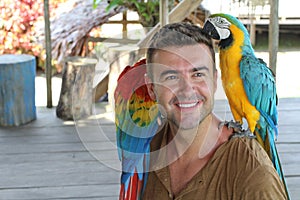 Handsome man interacting with two gorgeous macaws