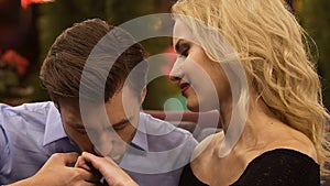 Handsome man kissing hand of blond woman, putting heads together, escort girl