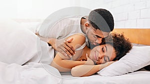 Handsome man kissing woman on cheek under in bed