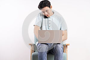 Handsome man with laptop sitting on sofa listening to the phone and working