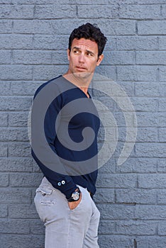 Handsome man leaning against gray wall